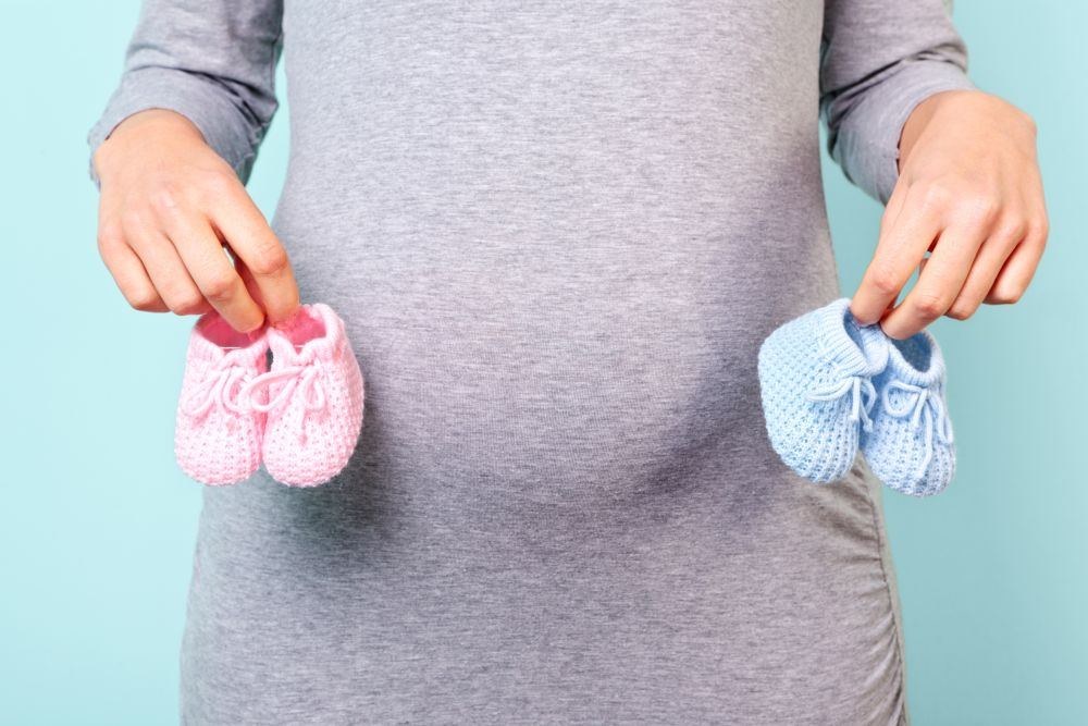 Nėščia moteris, rankose laikanti skirtingų spalvų vaikiškus batukus / Fotolia nuotr.