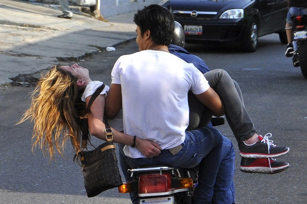 Genesis Carmona po šūvio išvežama iš protesto vietos / „Reuters“/„Scanpix“ nuotr.