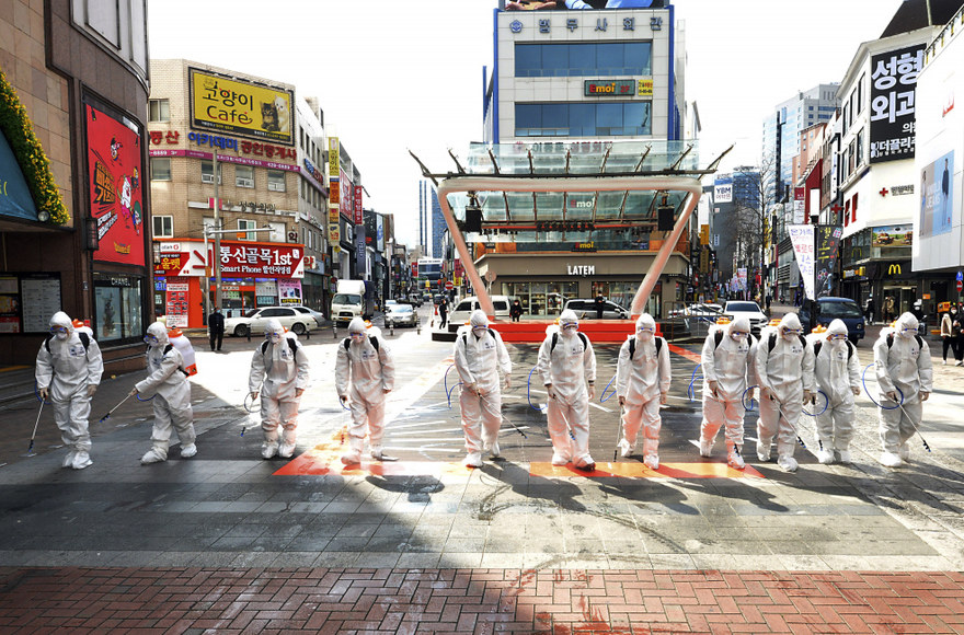 „Scanpix“/AP nuotr./Pietų Korėjos kareiviai, dėvintys apsauginius kostiumus, purškia dezinfekavimo priemones, siekiant išvengti COVID-19 plitimo
