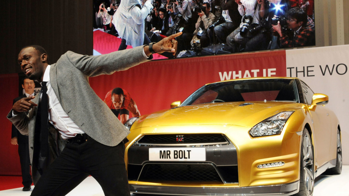 Usainas Boltas šalia savo auksinio „Nissan“ GT-R. / AFP/„Scanpix“ nuotr.