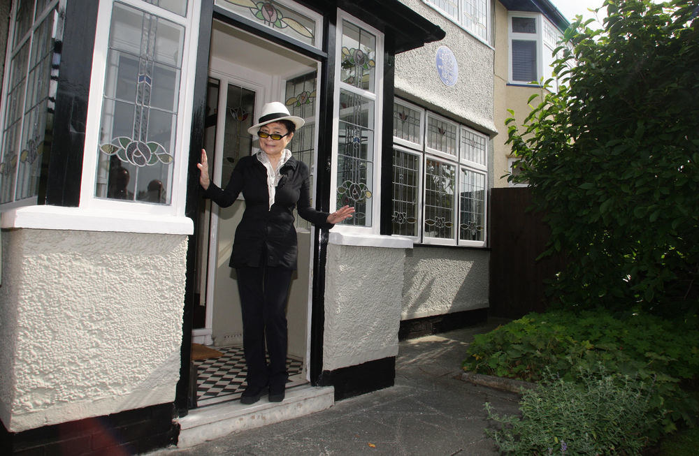 Yoko Ono stovi prie Johno Lennono dviejų butų namo, praminto „Mendips", esančio Menlav alėjoje Liverpulyje / „Scanpix“ nuotr.