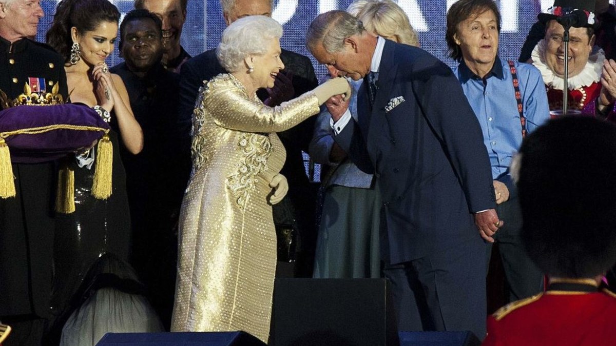Princas Charlesas scenoje galantiškai pabučiavo savo motinos karalienės Elizabeth II ranką. / AFP/„Scanpix“ nuotr.